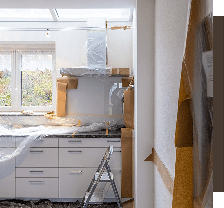 A kitchen being remodeled with white cabinets and a ladder.