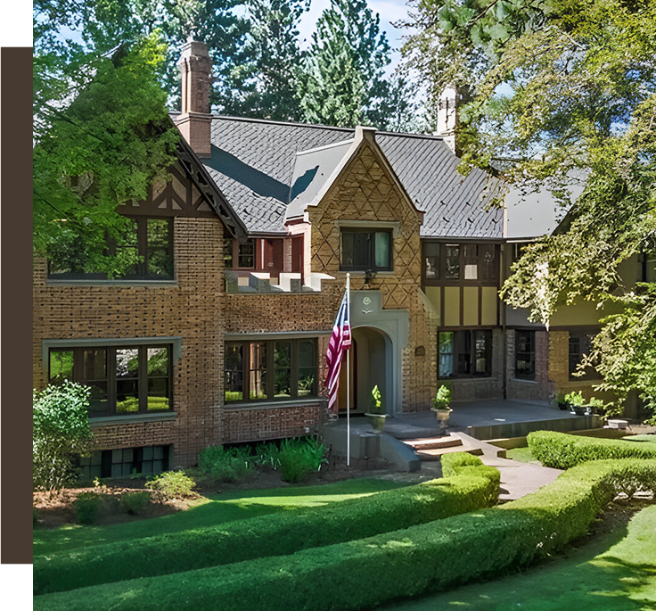 A large brick house with a flag on the front lawn.