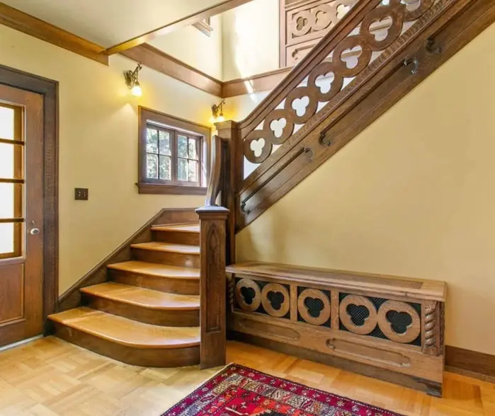 A wooden staircase with a rug on the floor.