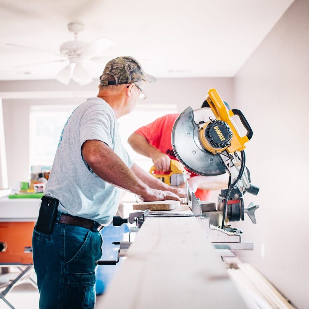 Two men working on a wall in a room.