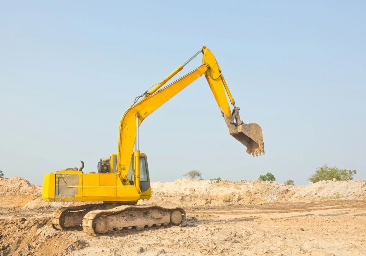 A yellow excavator is digging in the dirt.