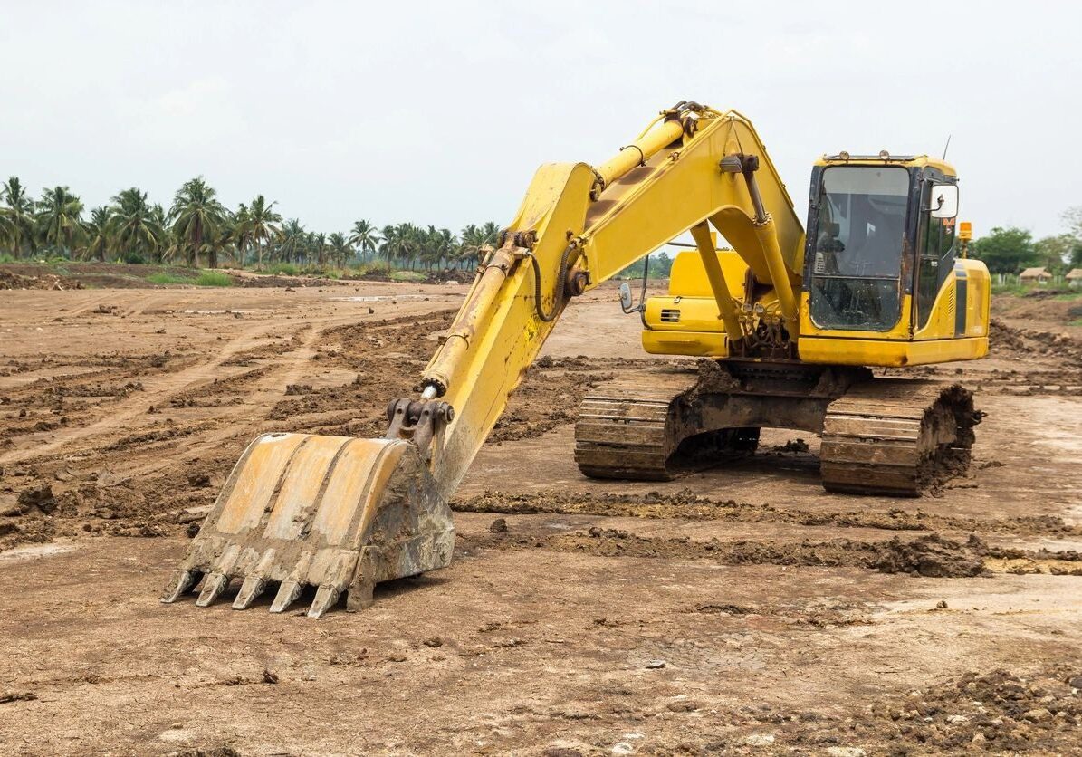 A yellow and black excavator on dirt ground