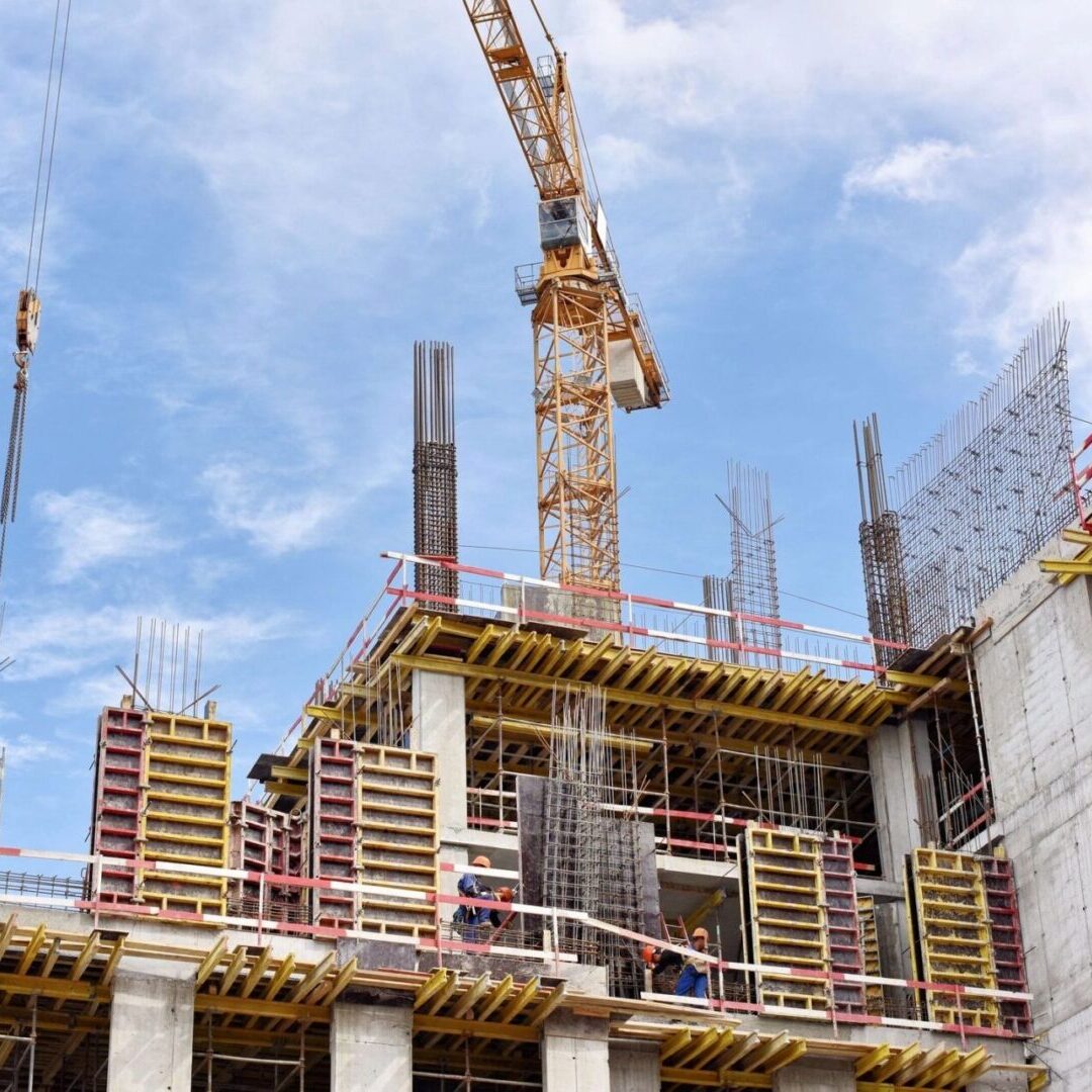 A building under construction with scaffolding and cranes.