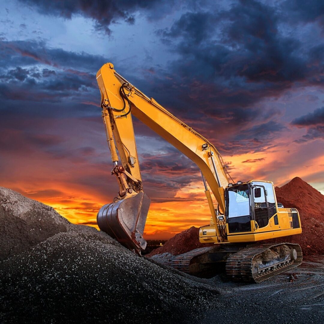 A yellow and black excavator on top of some rocks