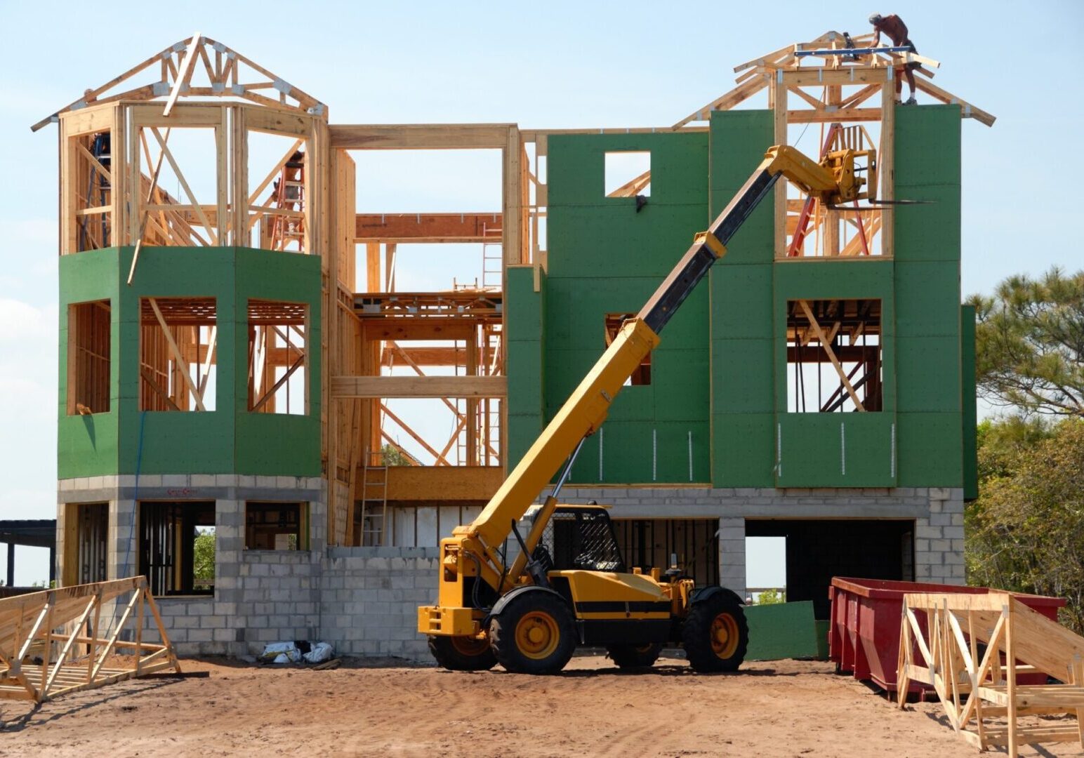 A crane is lifting up the walls of a house.